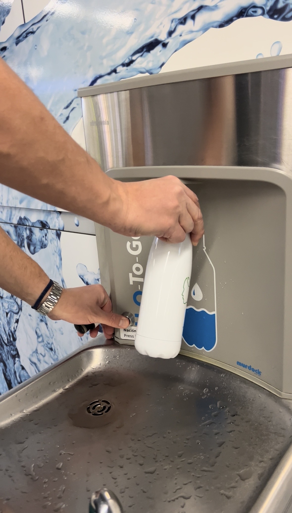 Someone filling a reusable bottle at a public refill point